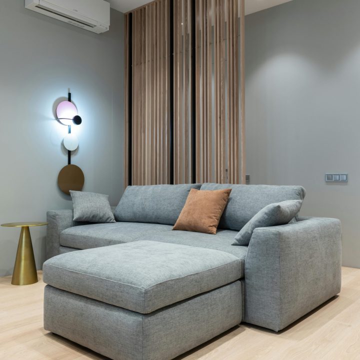 Interior of modern living room with sofa with pillows next to round table under conditioner